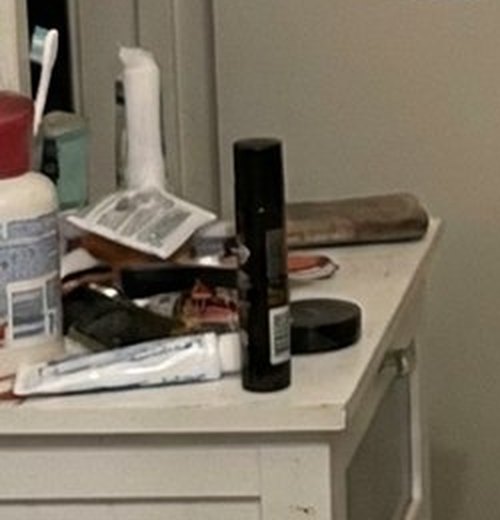 A cluttered bathroom counter with tubes of cream and small bottles